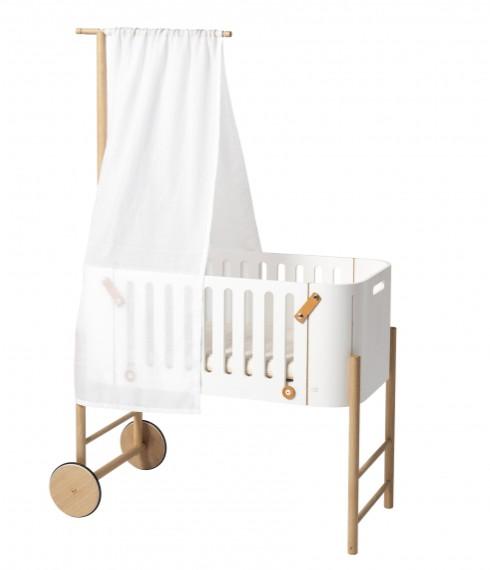 Oliver Furniture witte en eikenhouten co-sleeper naast een volwassen bed, omgezet naar een kinderbankje in een huiselijke setting.
