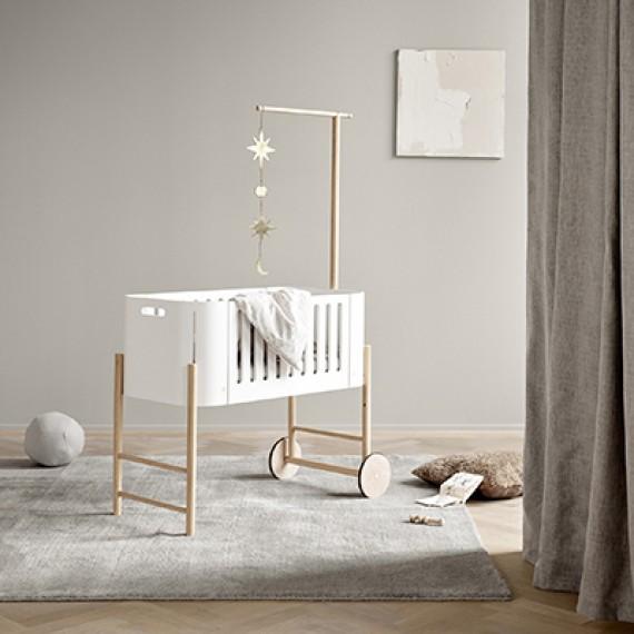 Oliver Furniture witte en eikenhouten co-sleeper naast een volwassen bed, omgezet naar een kinderbankje in een huiselijke setting.