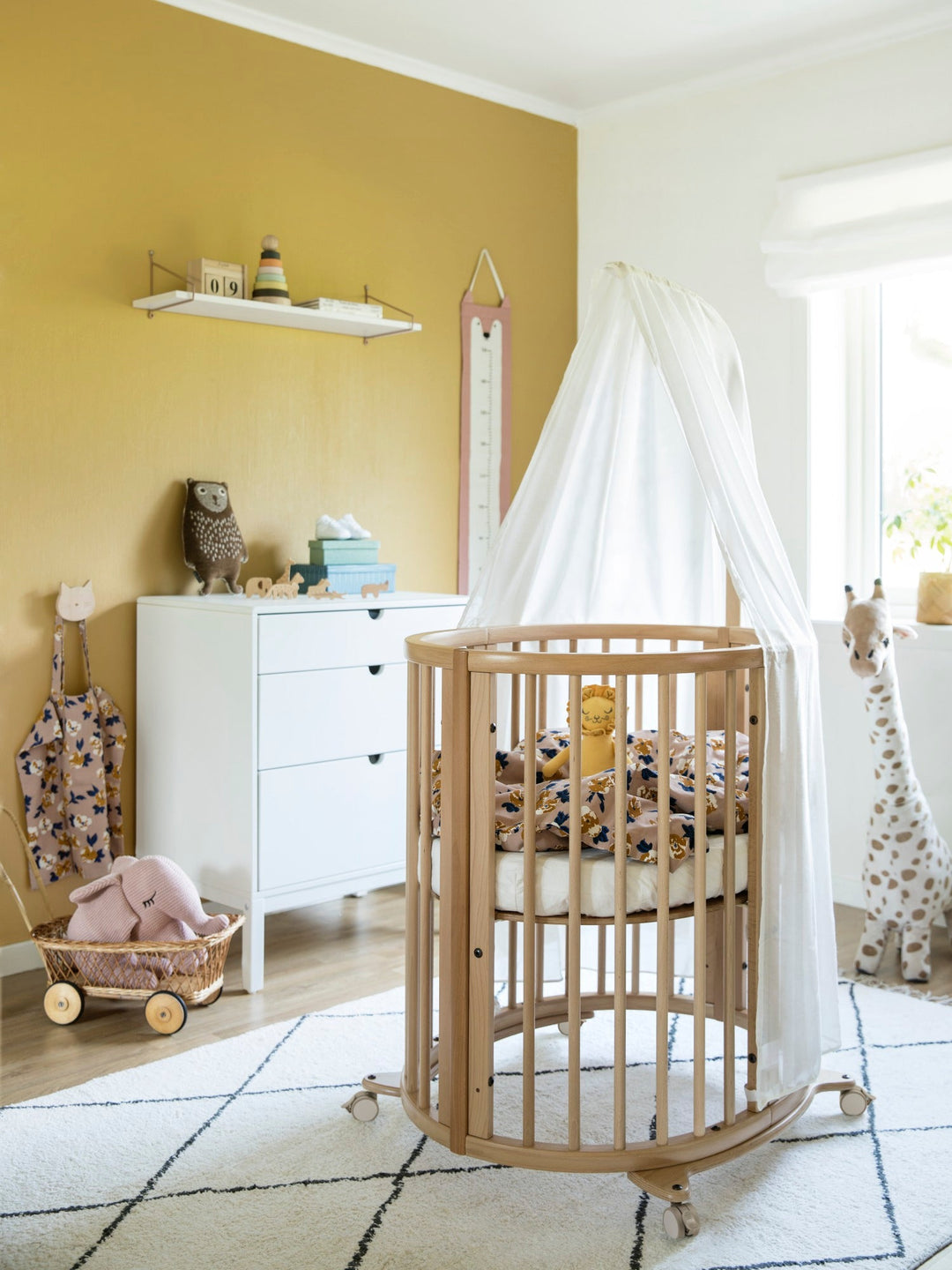 Stokke Sleepi™ V3 piekstok in natural finish, bevestigd aan een kinderbed, klaar voor het ophangen van een bedhemeltje