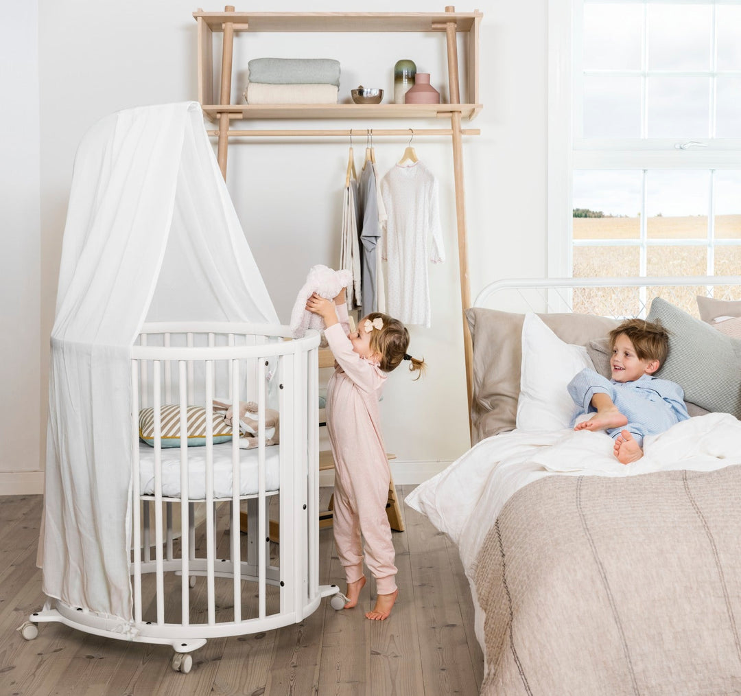 Stokke Sleepi™ V3 piekstok in white finish, bevestigd aan een kinderbed, klaar voor het ophangen van een bedhemeltje