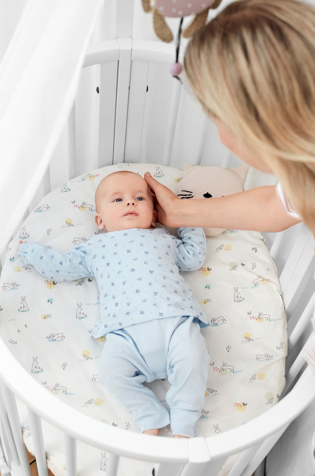 Stokke Sleepi™ Mini V3 wieg in wit, met zachte ovale vorm en vergrendelbare zwenkwielen.