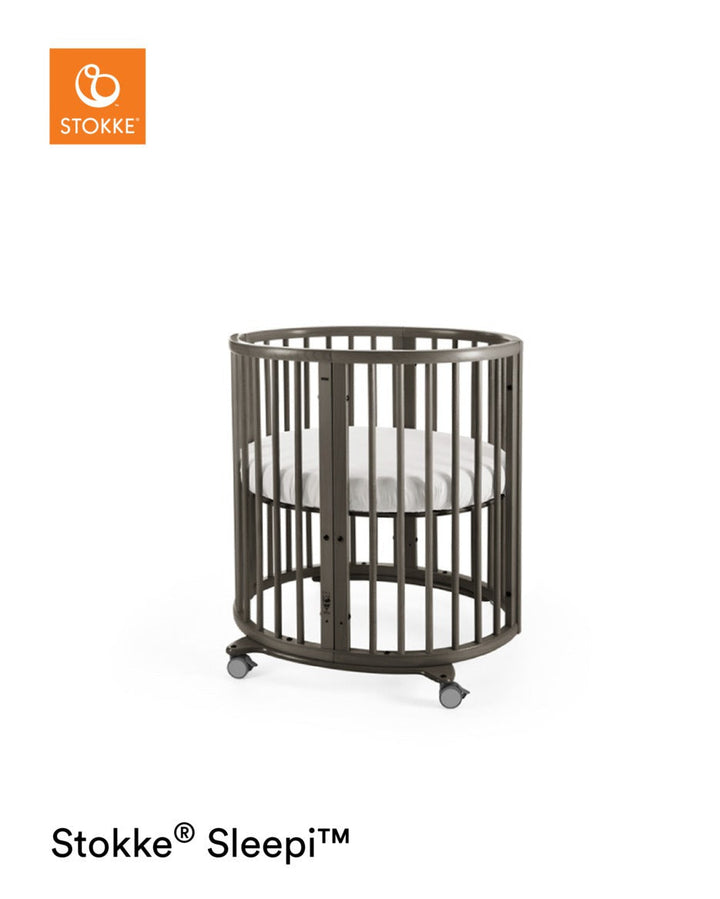 Stokke Sleepi™ Mini V3 wieg in hazy grey afwerking, met zachte ovale vorm en vergrendelbare zwenkwielen.