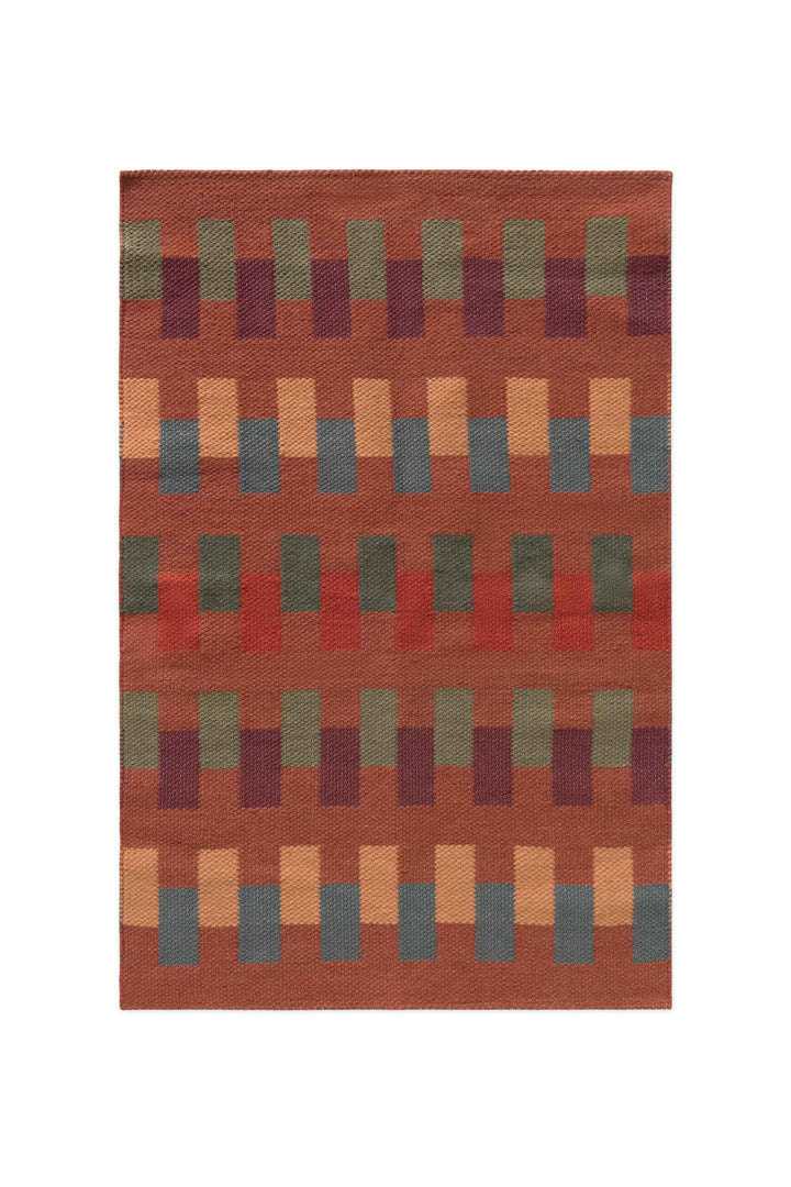 Lorena Canals Intersecting tapijt Sienna 86x130 cm met geometrische vlakken in groen, blauw, oker en bordeaux.
