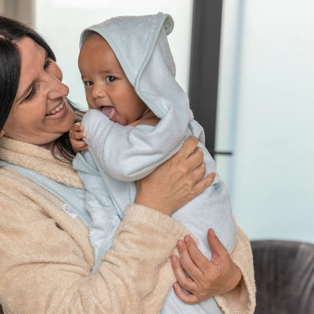 Timboo poncho cuddle towel in Riviera Blue, gedragen als schort door ouder met baby