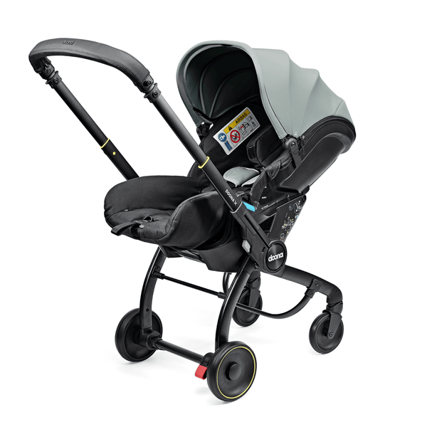 Doona X autostoel in Dusty Sage, omgevormd tot kinderwagen met verstelbare hoofdsteun en faux-leather handgreep.