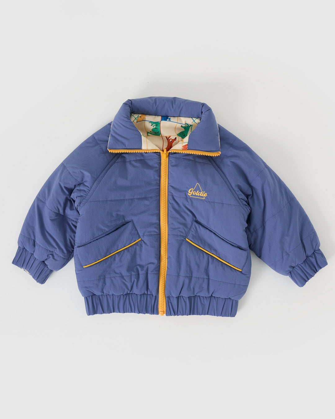 Kind draagt omkeerbare blauwe pufferjas met kangoeroeprint van Goldie + Ace