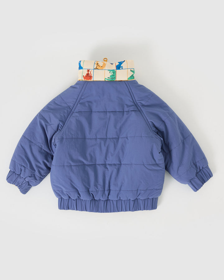 Kind draagt omkeerbare blauwe pufferjas met kangoeroeprint van Goldie + Ace