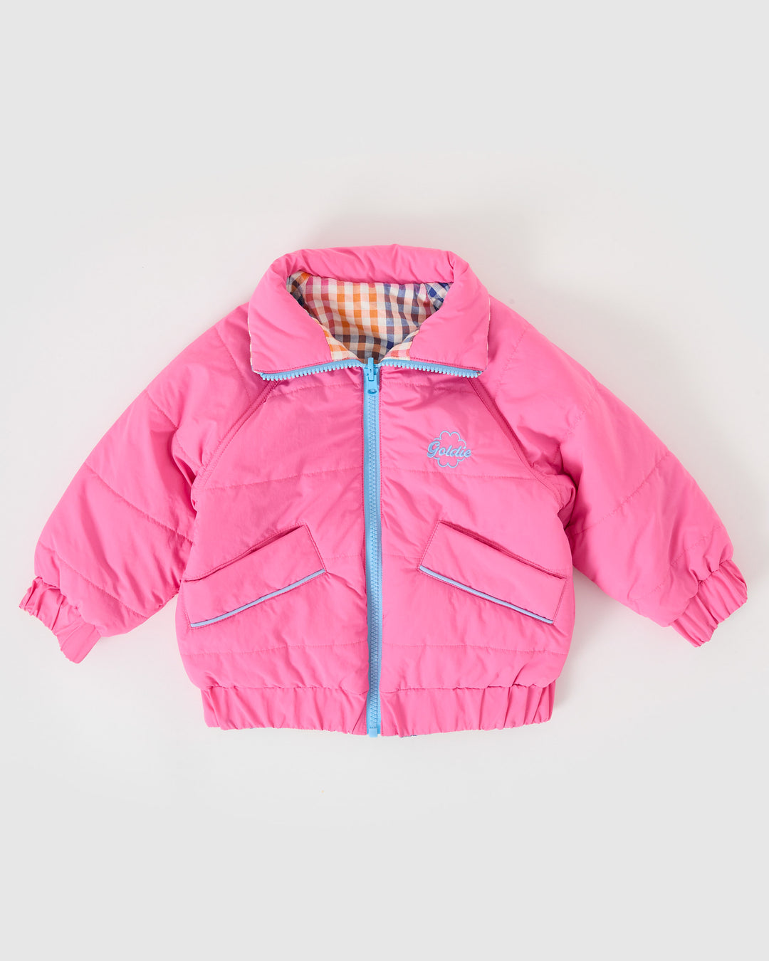 Kind draagt omkeerbare roze pufferjas met regenboogruit van Goldie + Ace