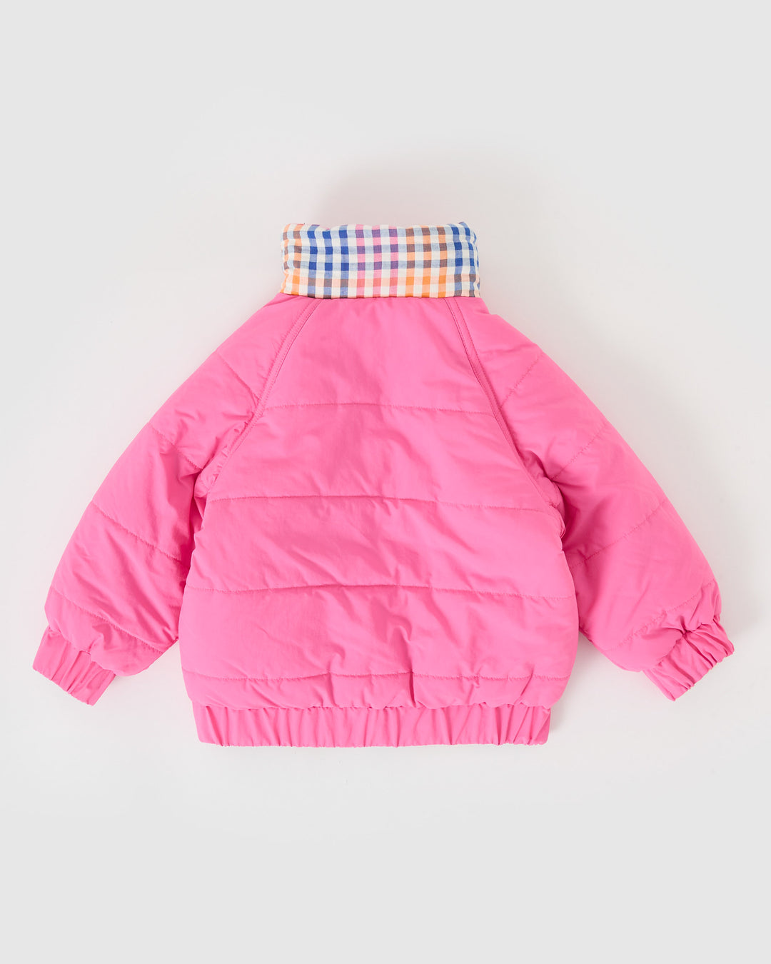 Kind draagt omkeerbare roze pufferjas met regenboogruit van Goldie + Ace