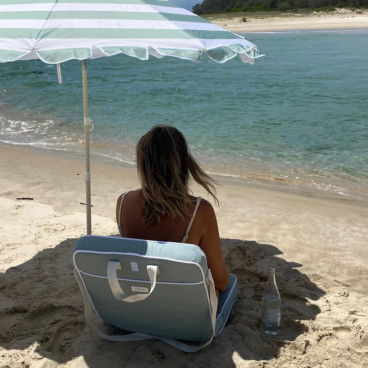 Sunnylife Parasol Compact La Palma in groen-wit gestreept design op het strand