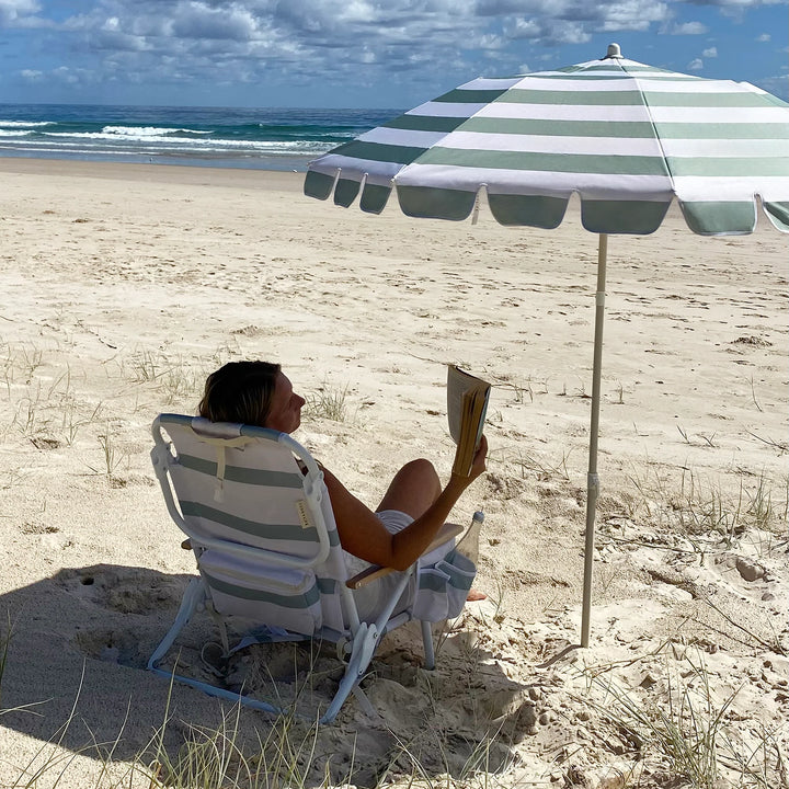 Sunnylife Parasol Compact La Palma in groen-wit gestreept design op het strand