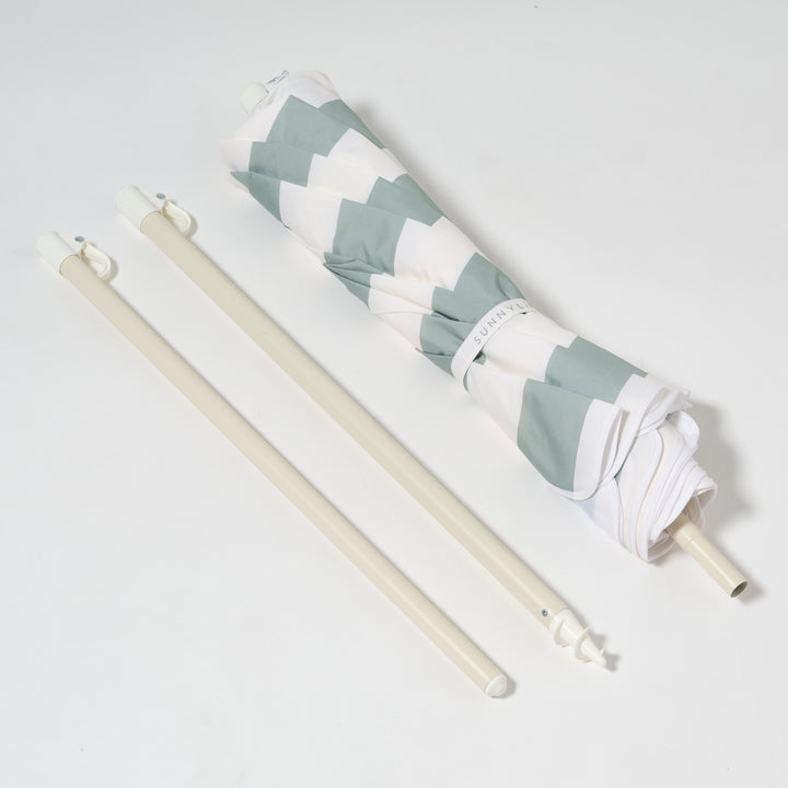 Sunnylife Parasol Compact La Palma in groen-wit gestreept design op het strand