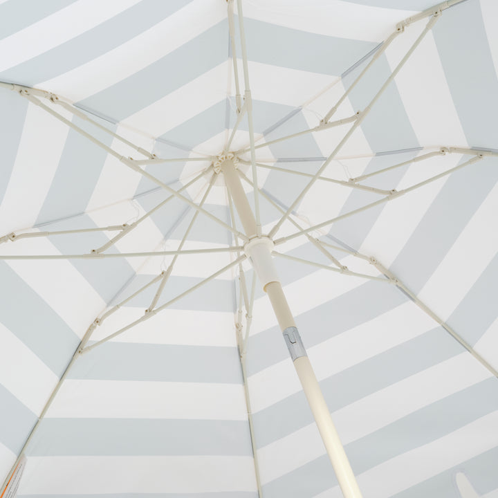Sunnylife Parasol Compact La Palma in groen-wit gestreept design op het strand