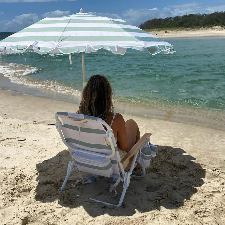 Sunnylife Parasol Compact La Palma in groen-wit gestreept design op het strand