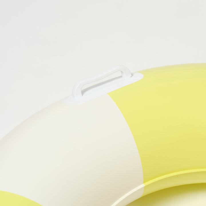 Slanke zwemband met gele strepen van Sunnylife, drijvend in helder zwembadwater