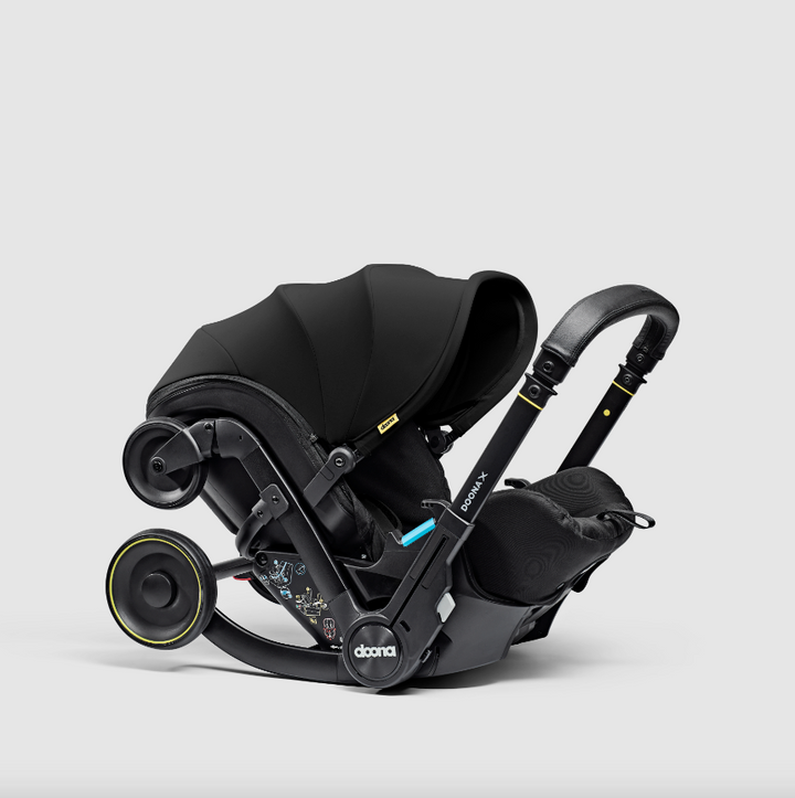 Doona X autostoel in Nitro Black, omgevormd tot kinderwagen met verstelbare hoofdsteun en faux-leather handgreep.