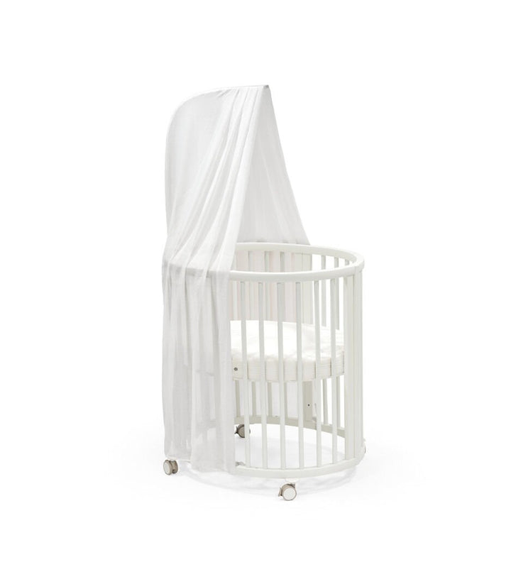 Stokke Sleepi™ Mini V3 wieg in wit, met zachte ovale vorm en vergrendelbare zwenkwielen.