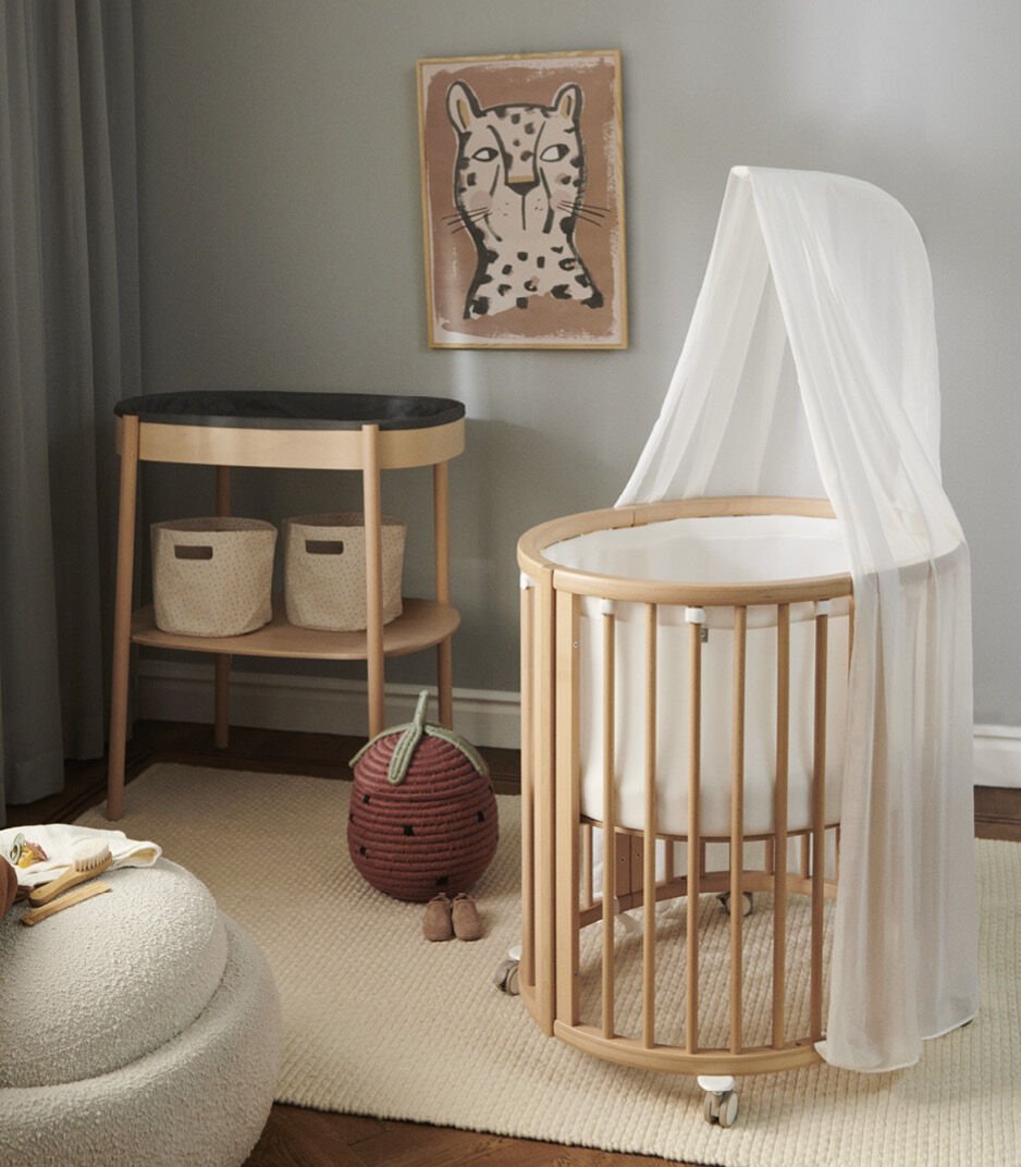 Stokke Sleepi™ V3 piekstok in natural finish, bevestigd aan een kinderbed, klaar voor het ophangen van een bedhemeltje