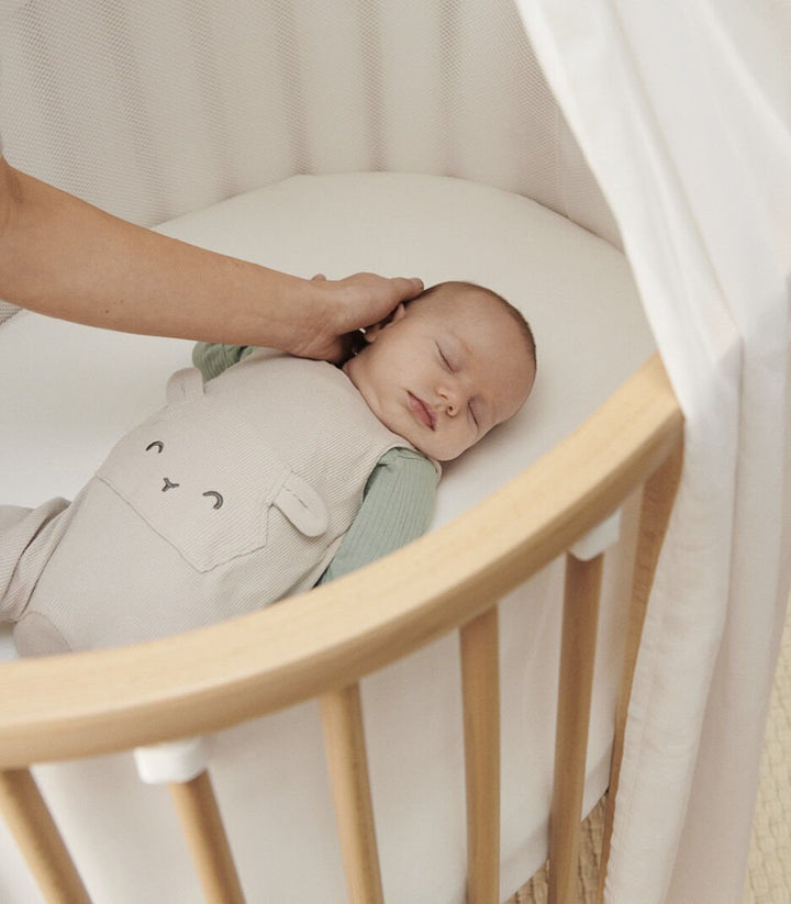 Stokke Sleepi V3 bedhemeltje in wit, bevestigd aan de piekstok, creëert een rustgevende en veilige slaapomgeving voor baby's