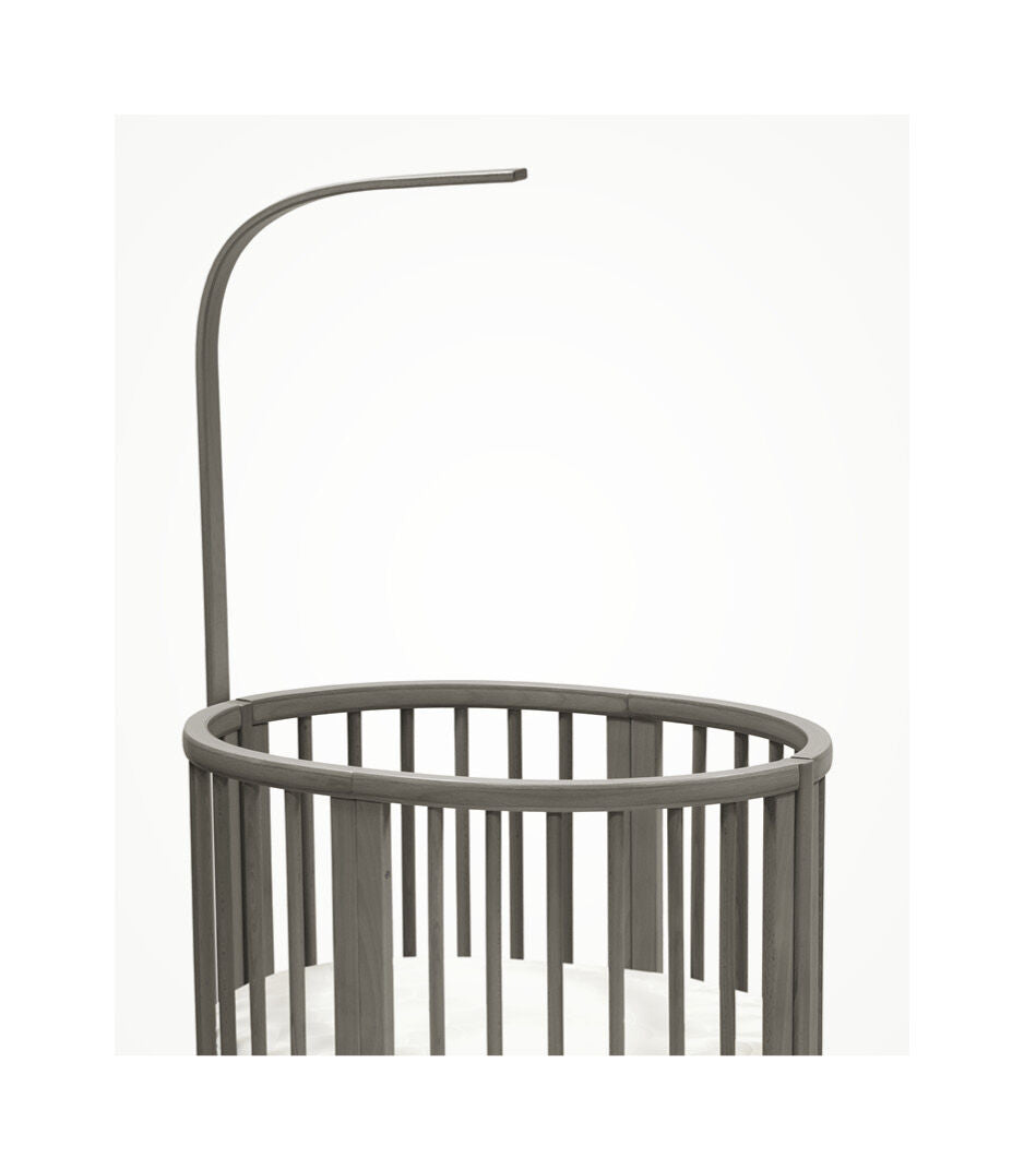 Stokke Sleepi™ V3 piekstok in hazy grey finish, bevestigd aan een kinderbed, klaar voor het ophangen van een bedhemeltje