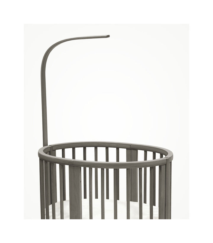 Stokke Sleepi™ V3 piekstok in hazy grey finish, bevestigd aan een kinderbed, klaar voor het ophangen van een bedhemeltje
