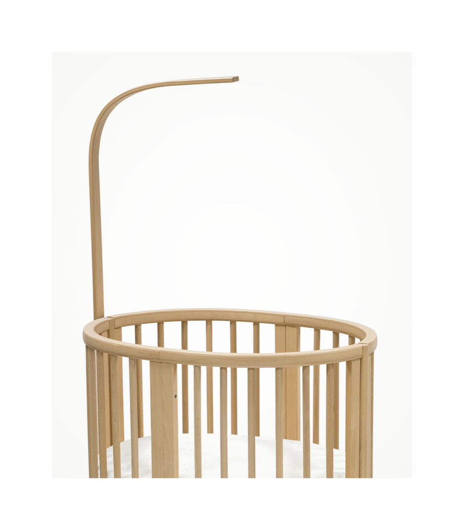 Stokke Sleepi™ V3 piekstok in natural finish, bevestigd aan een kinderbed, klaar voor het ophangen van een bedhemeltje